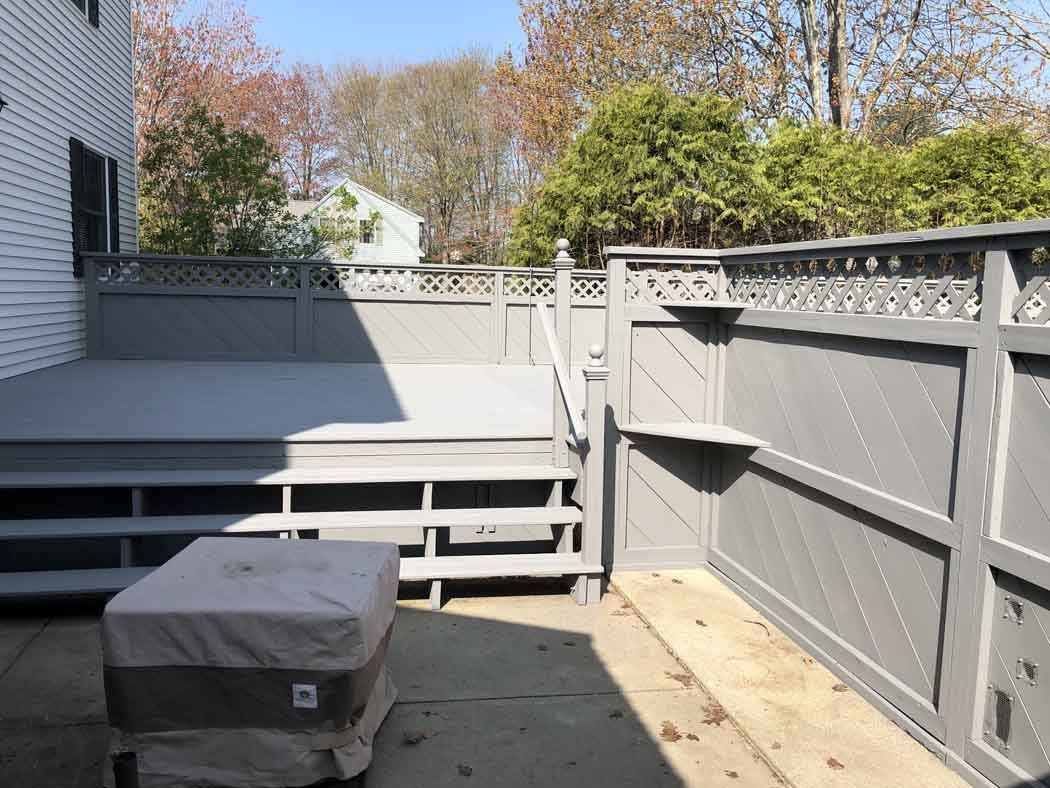 A patio with a table and chairs and a fence.