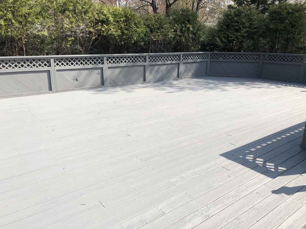A large empty deck with a fence and trees in the background.