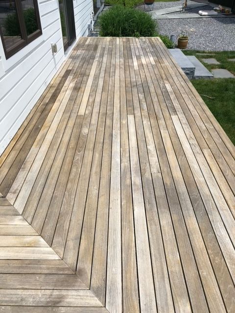 A wooden deck with a white house in the background