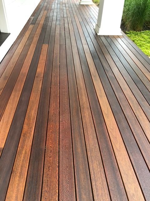 A wooden deck with a white porch in the background