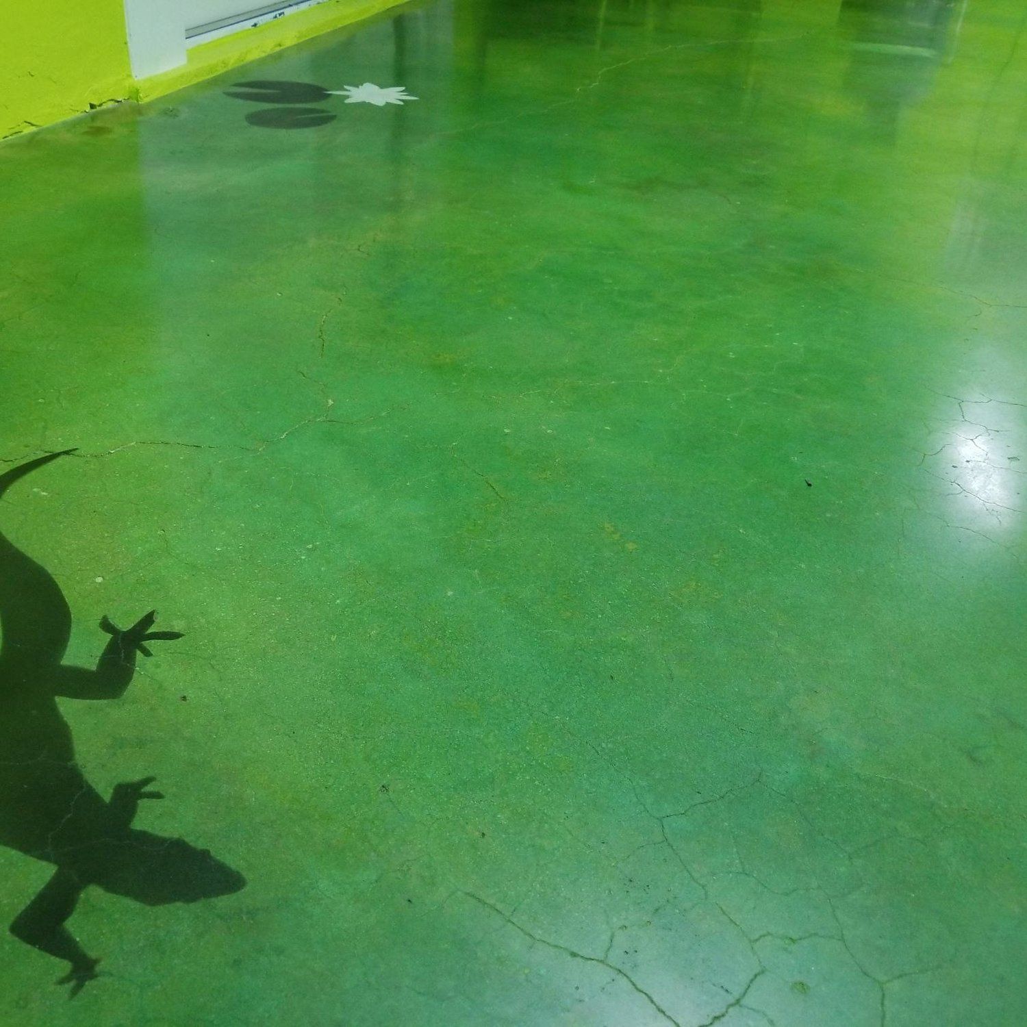 Green floor with a cracked surface and a dark lizard silhouette at the lower left.