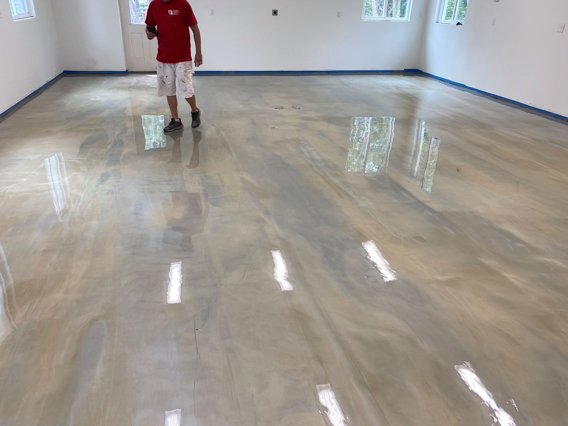 Person standing in a large empty room with a glossy, freshly finished floor