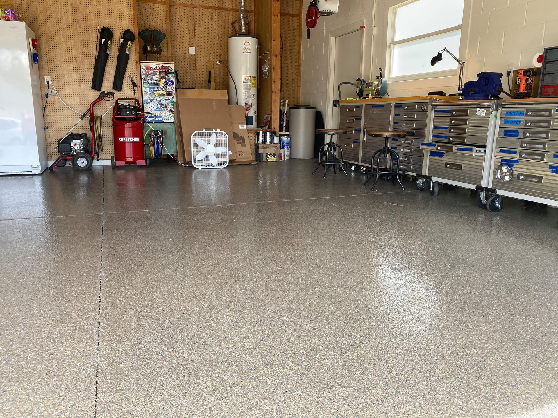 Spacious garage with polished speckled floor, workbench, tools, and storage cabinets along the walls