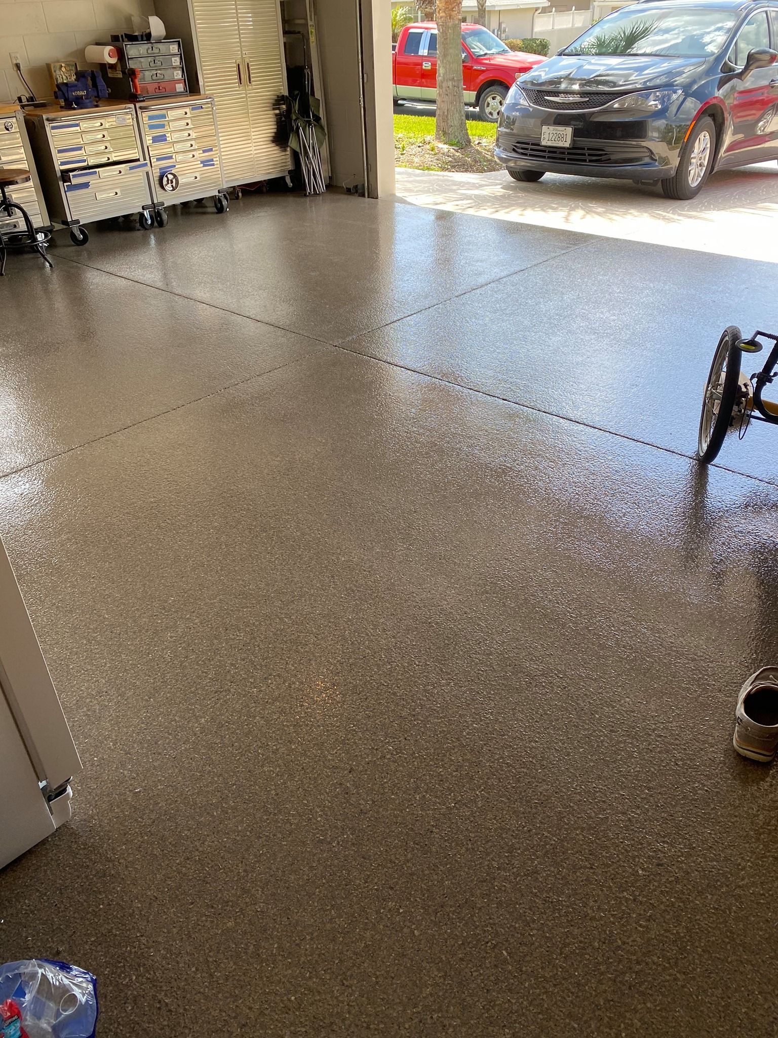 Freshly coated speckled garage floor with an open door and parked cars outside