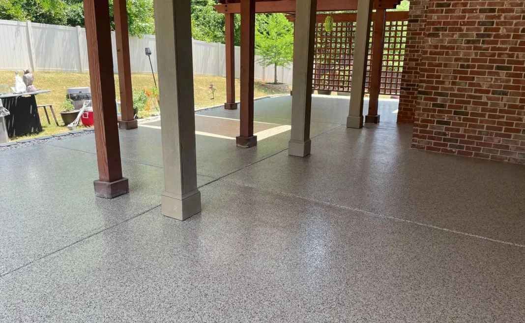 Covered patio with brick columns, concrete floor, and a view of a yard beyond the railing