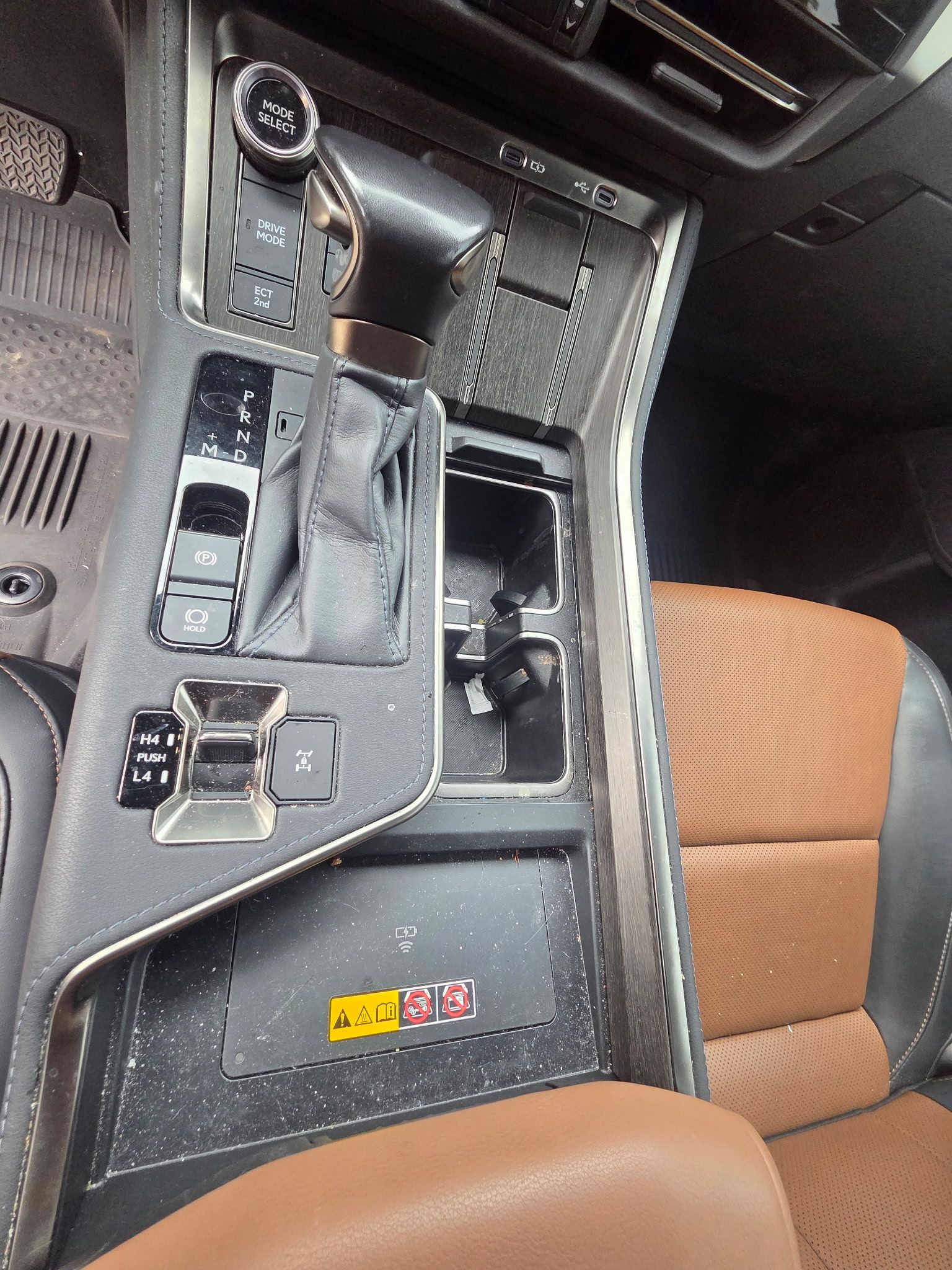 A dusty, tan-colored car interior door panel with a wood-grain trim accent and visible speaker and window control.