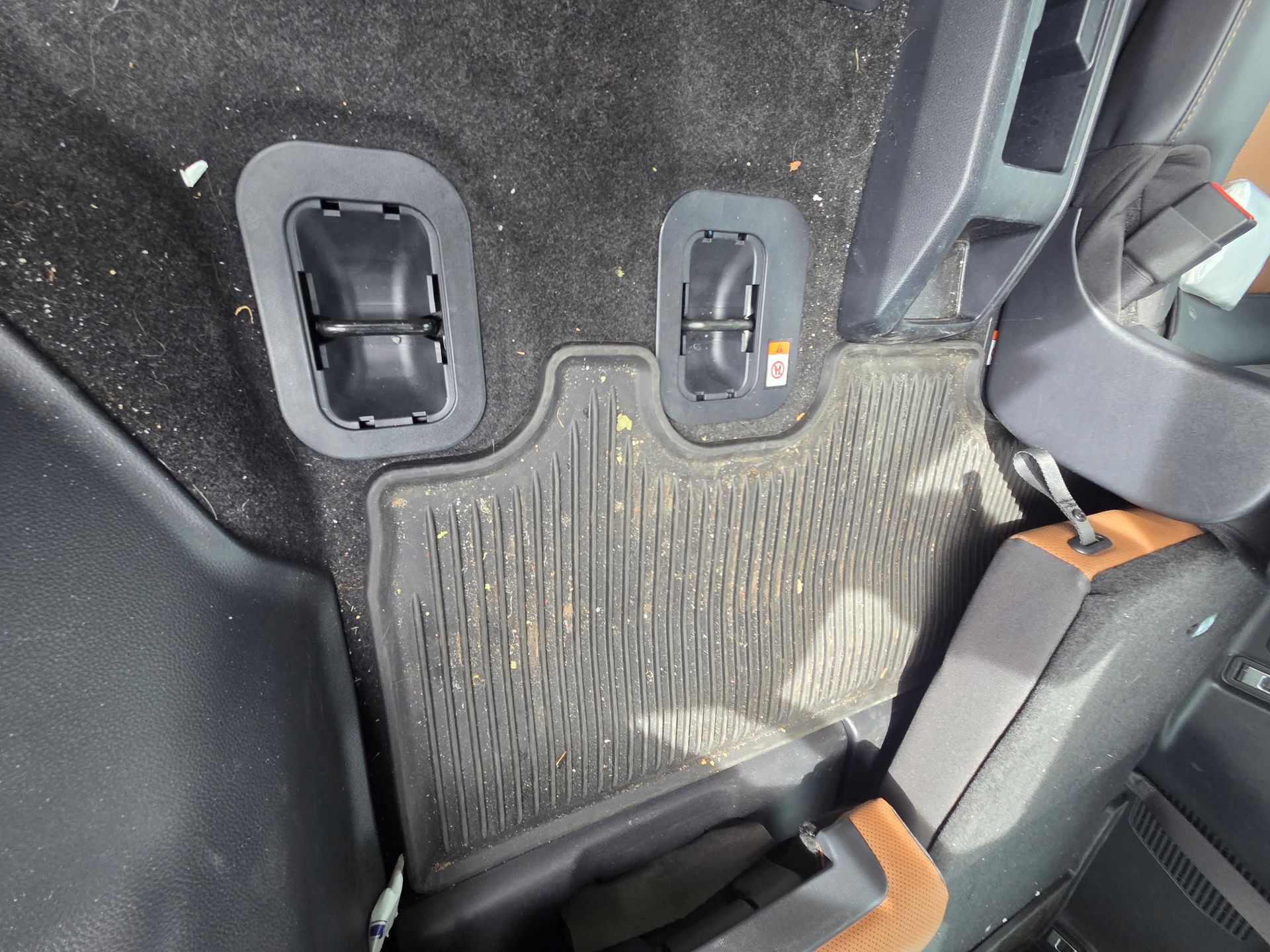 A black minivan parked on a residential driveway with its front passenger door open, covered in light snow or frost.