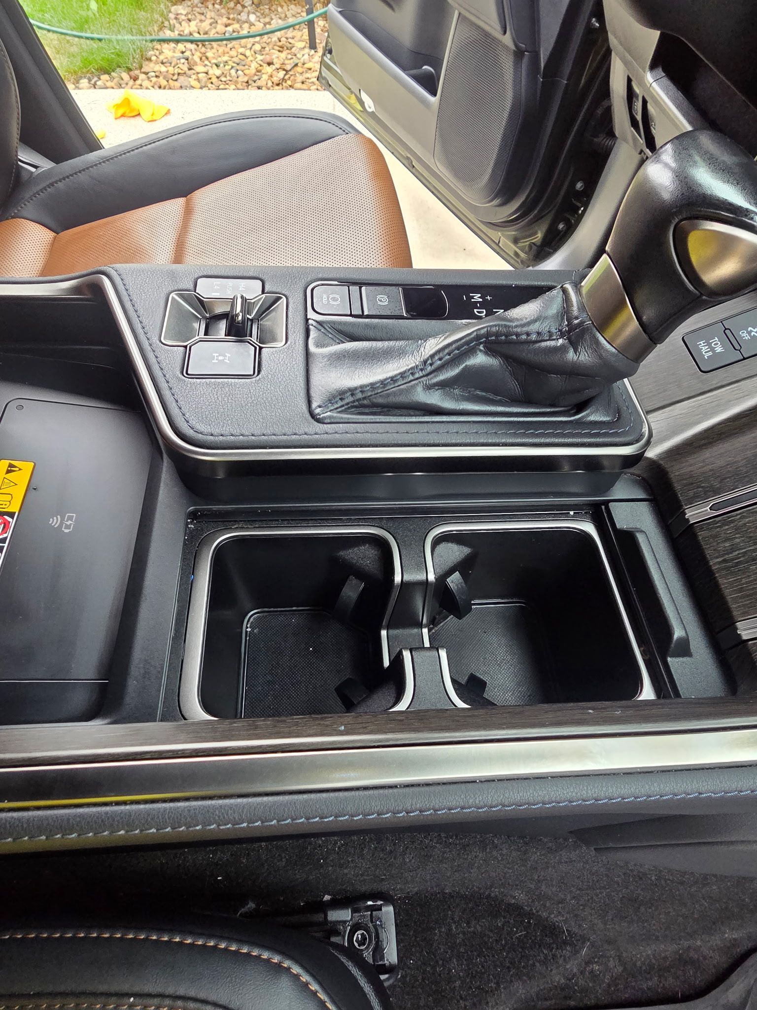 Interior view of a tan car door panel featuring a wood-grain trim accent, a window control switch, and a speaker grille.
