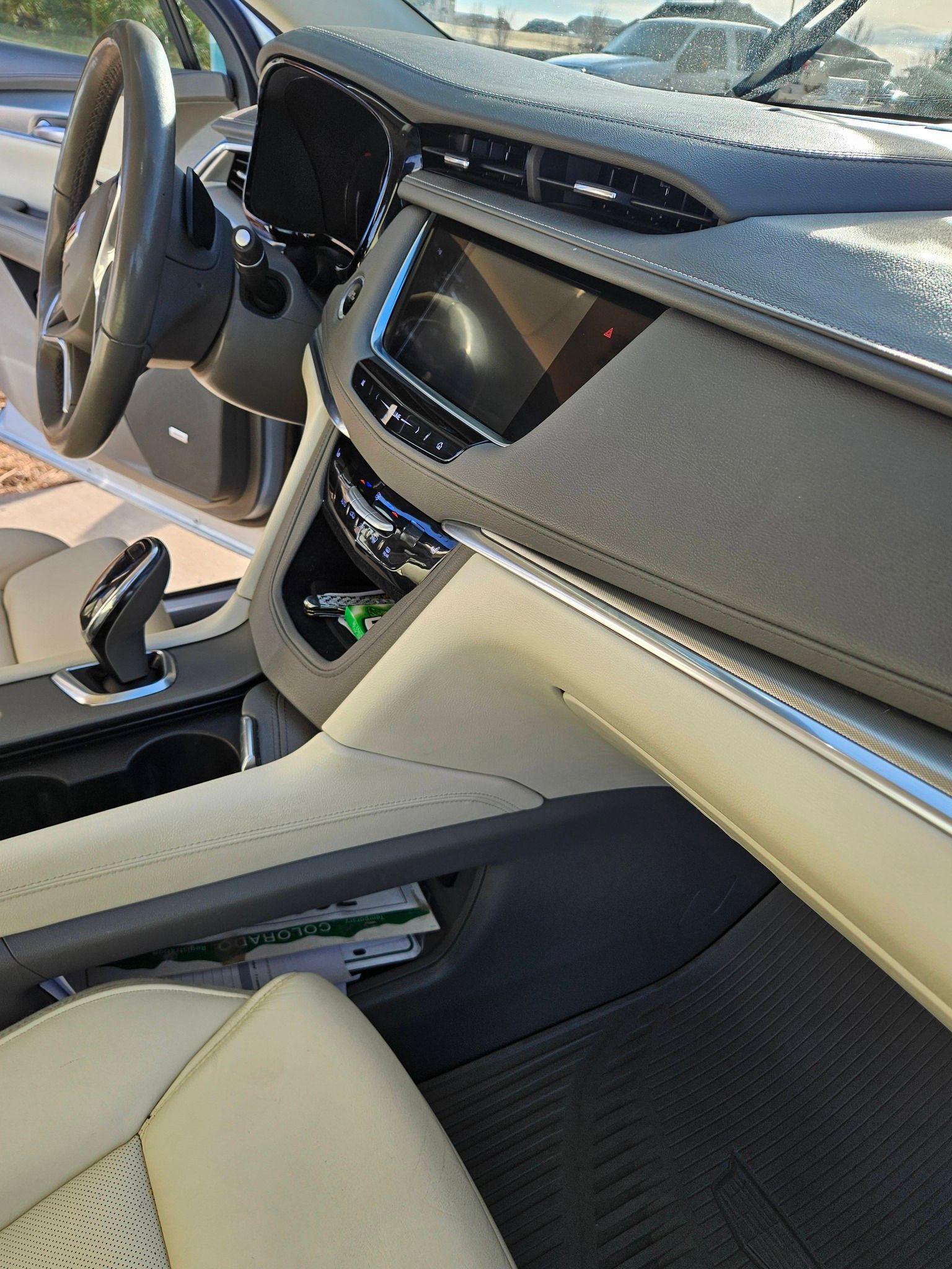 Interior view of a vehicle dashboard featuring a beige leather console, steering wheel, and a center infotainment screen.