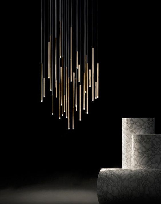 Cluster of vertical pendant lights with a sleek metallic finish against a black background.