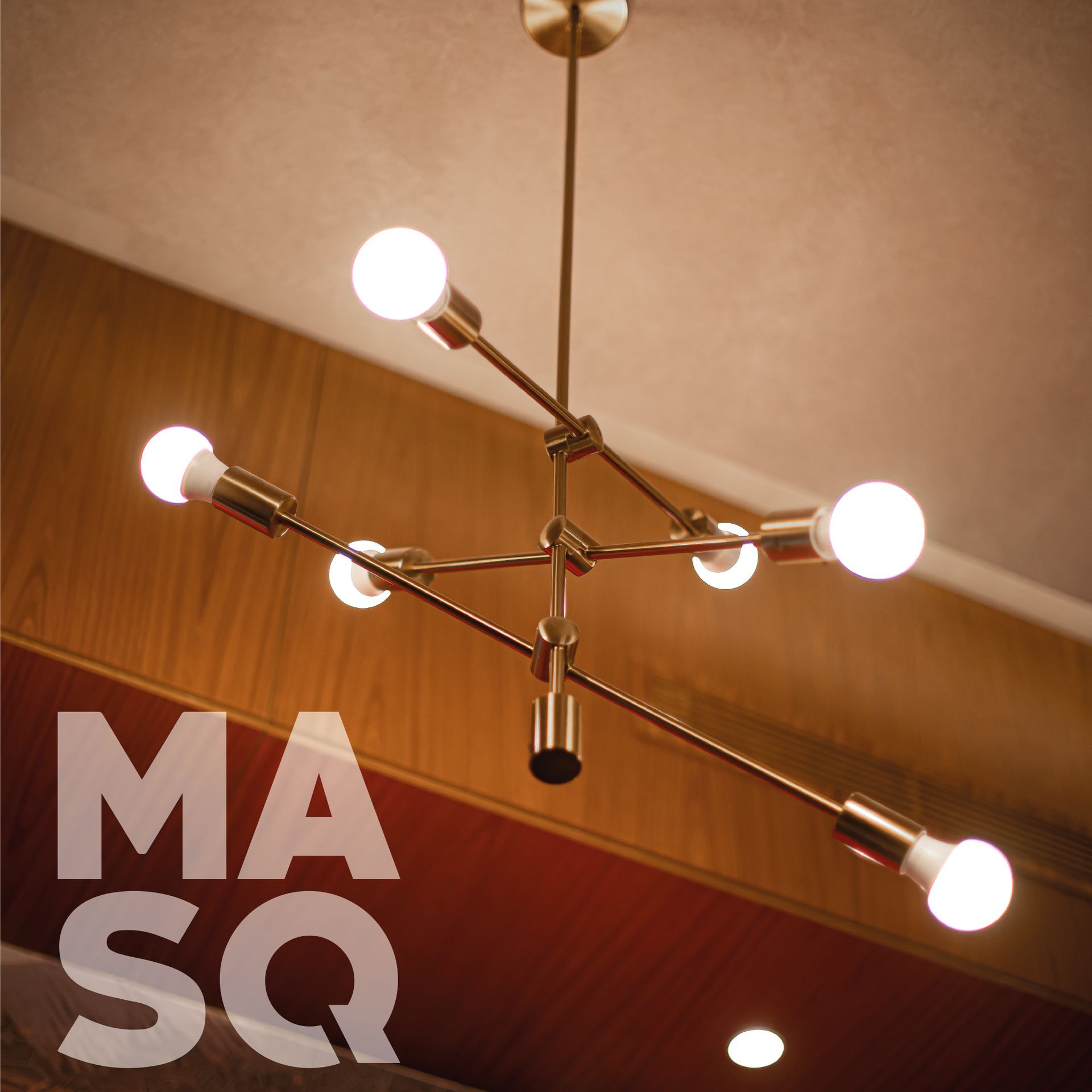 Close-up of a sleek, modern chandelier with metallic arms and round bulbs, hanging from a minimalist ceiling.