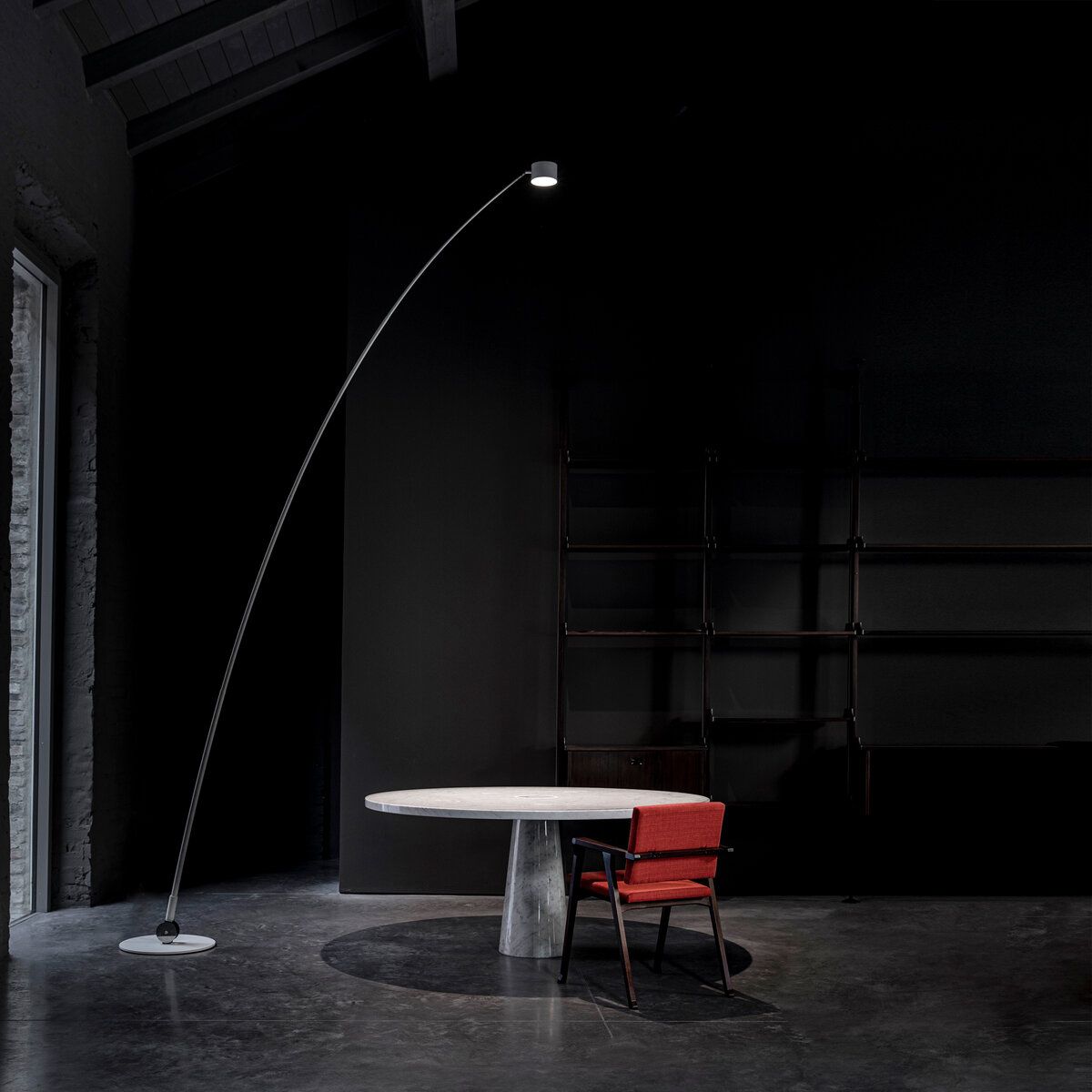 Dark minimalist interior with a sleek arched floor lamp lighting up the space.