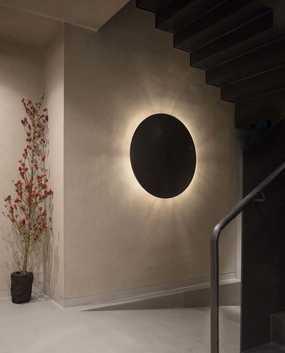 Circular wall-mounted light with a soft glow, enhancing a modern staircase area.