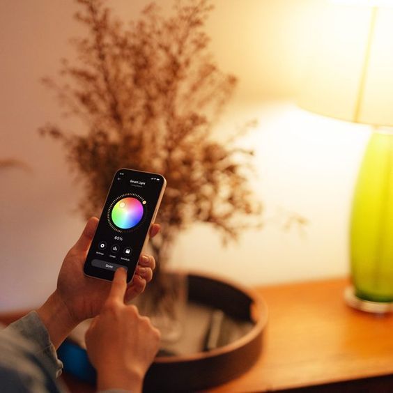 Smartphone controlling a smart light bulb, with color selection visible on the screen.