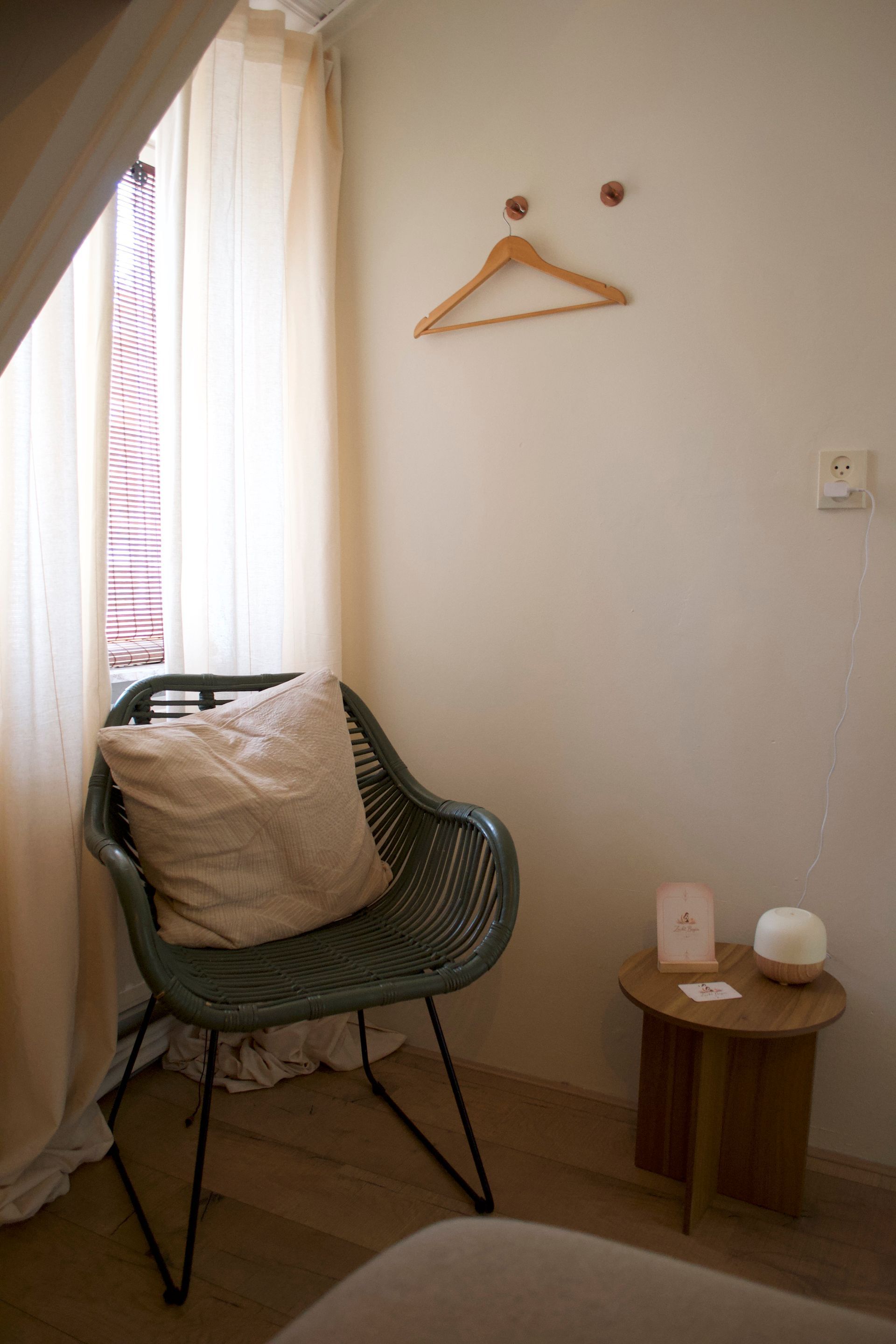 Een knusse, kleine kamerhoek met een groene stoel, een beige kussen.