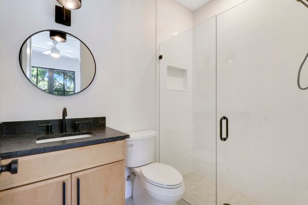 A bathroom with a toilet , sink , mirror and shower.