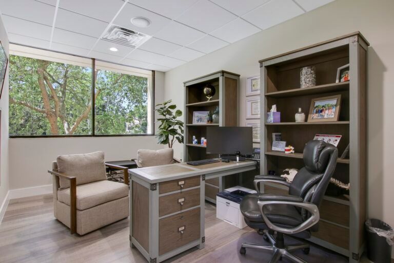 A home office with a desk , chair , bookshelf and computer.