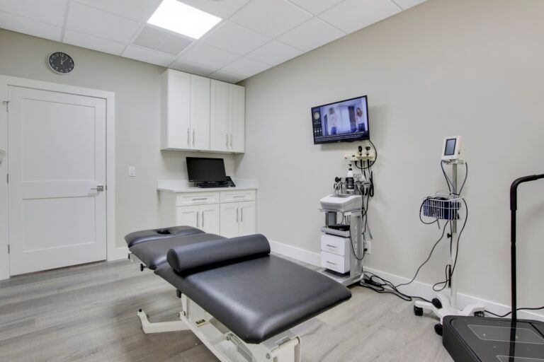 A doctor 's office with a bed and a treadmill.