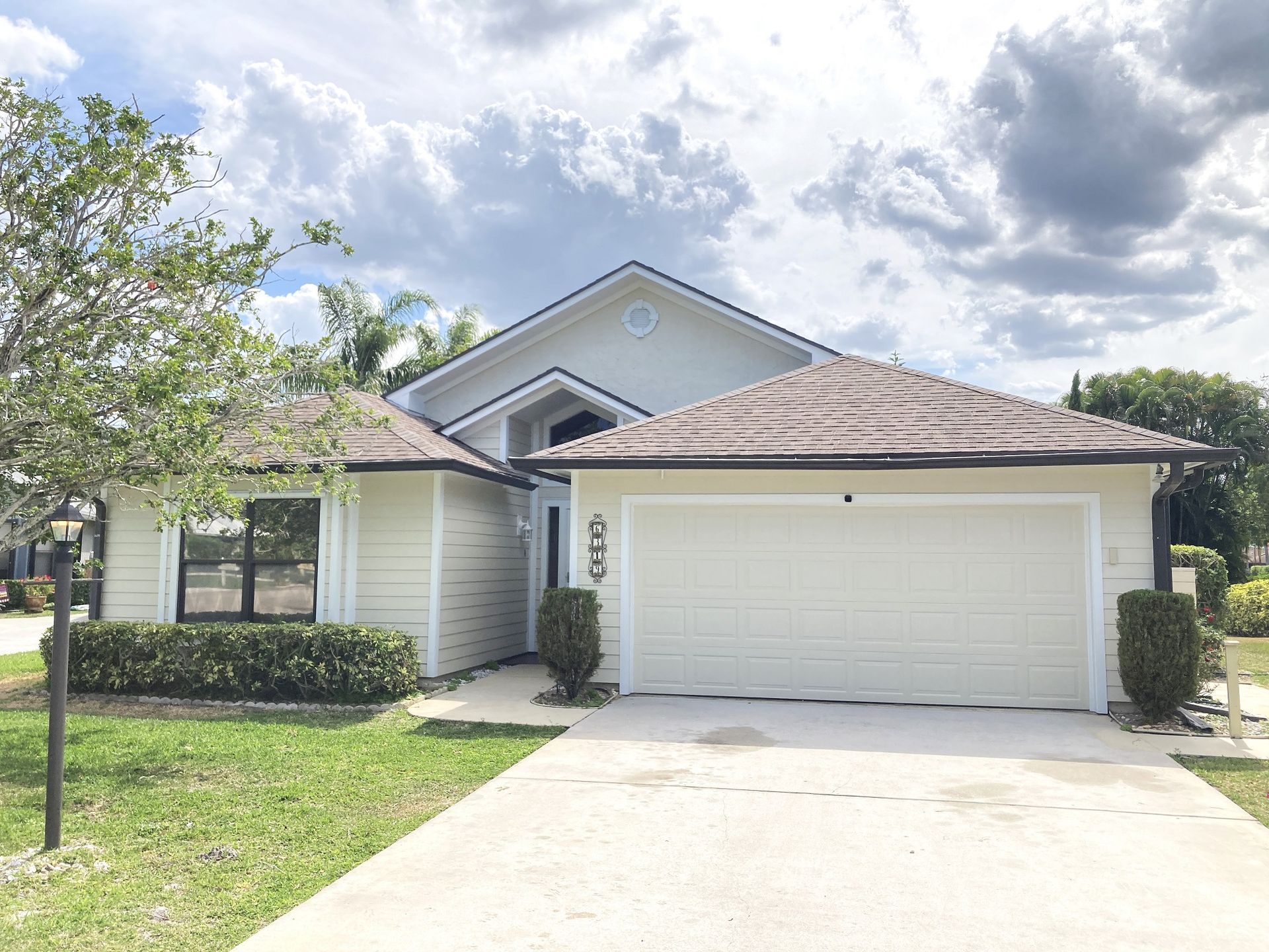A white house with a brown roof and a white garage door.