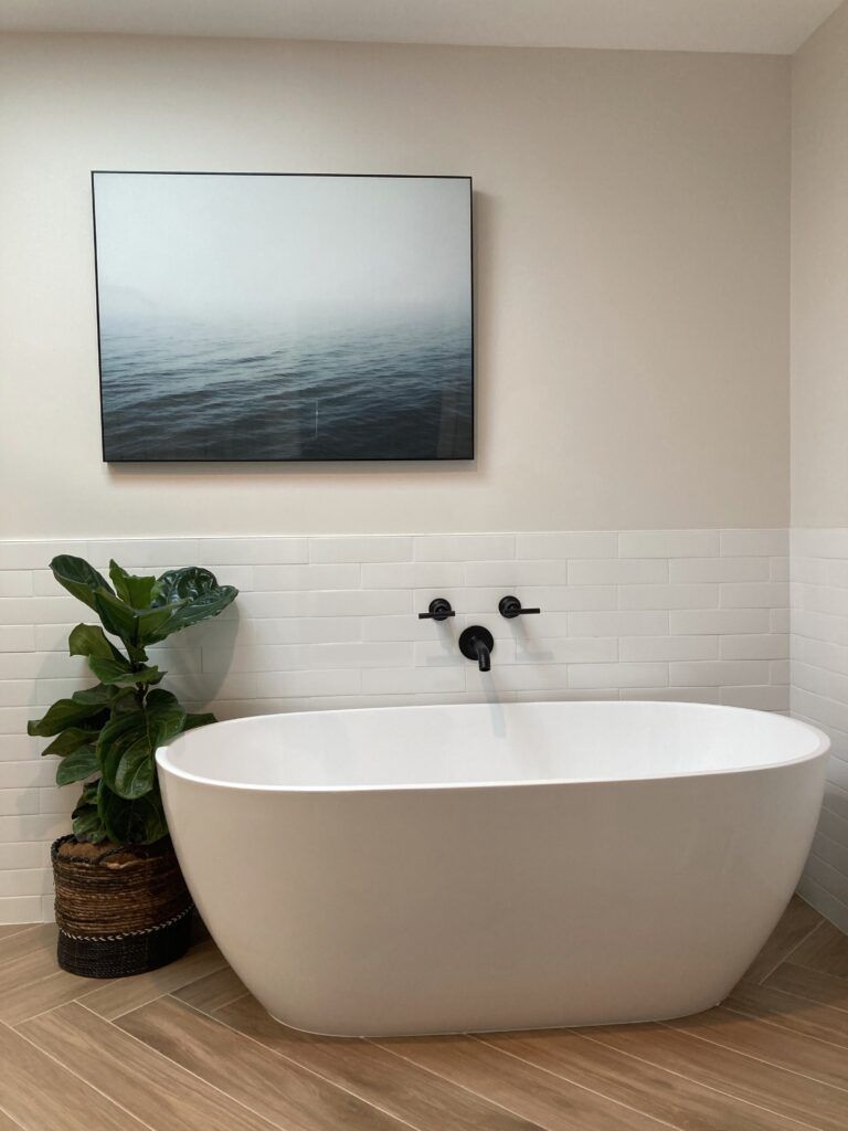 A bathroom with a bathtub and a painting on the wall above it.