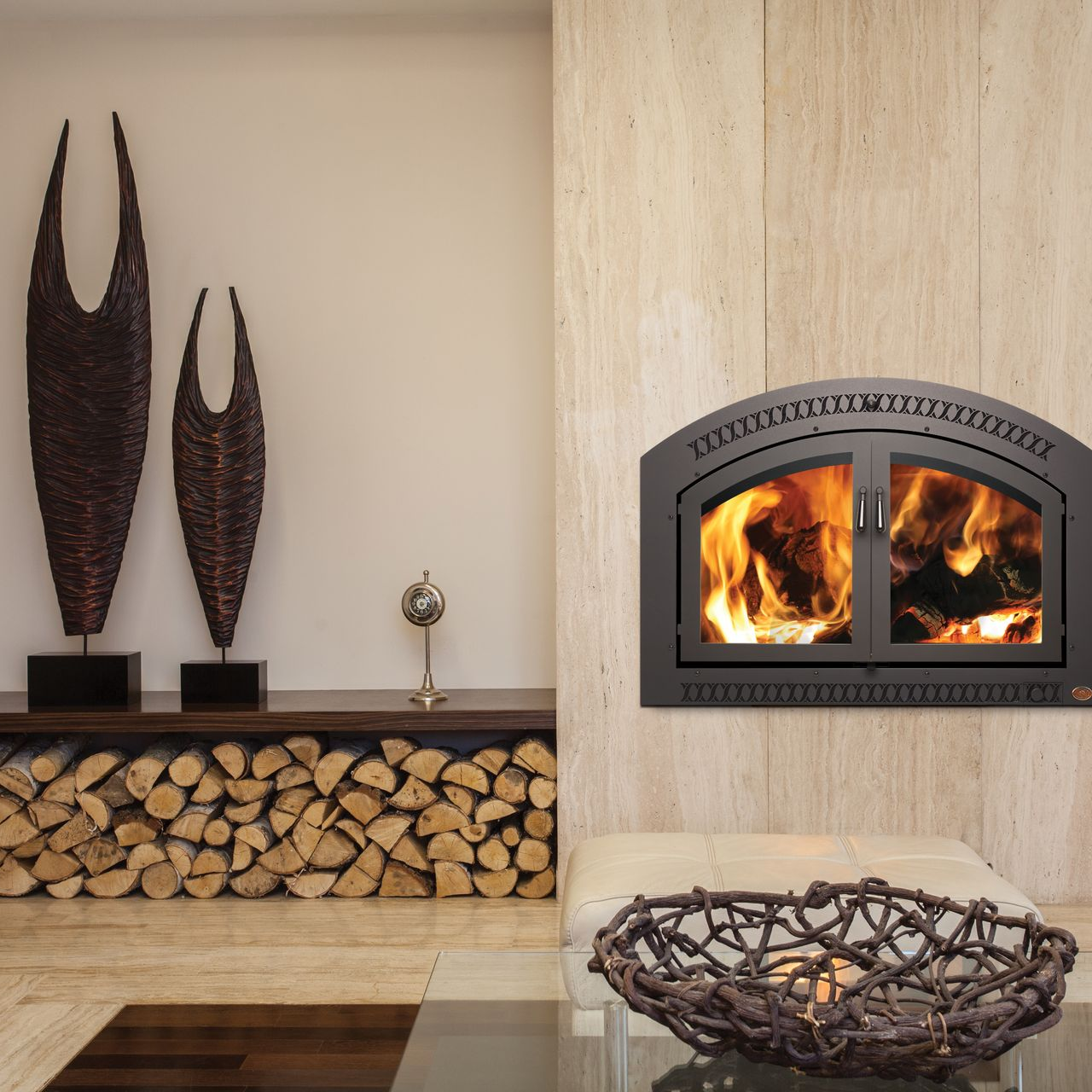 Modern living room with a lit fireplace, stacked firewood, and tall decorative sculptures on a mantel