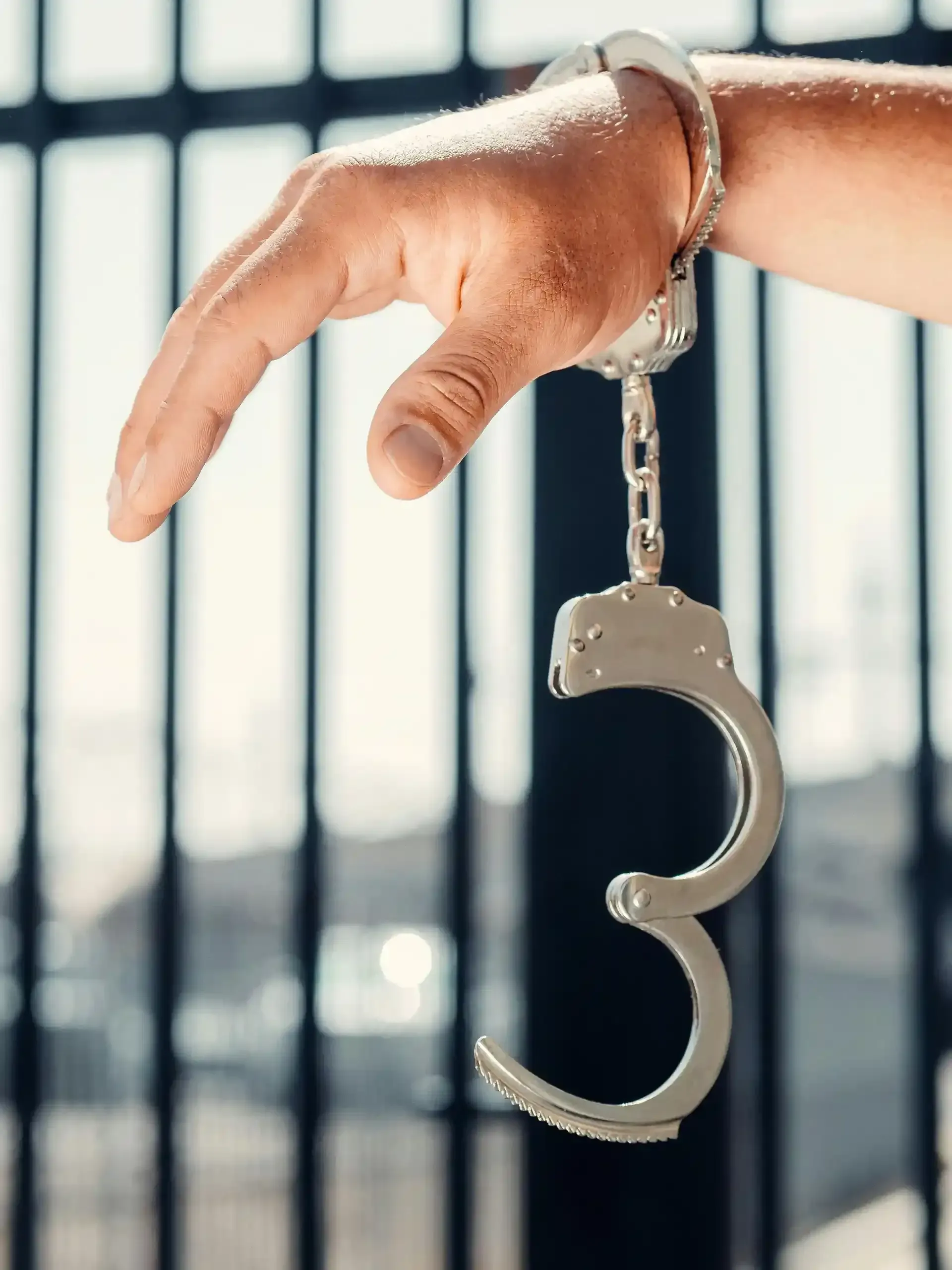 Handcuffed hand dangling in front of a window.
