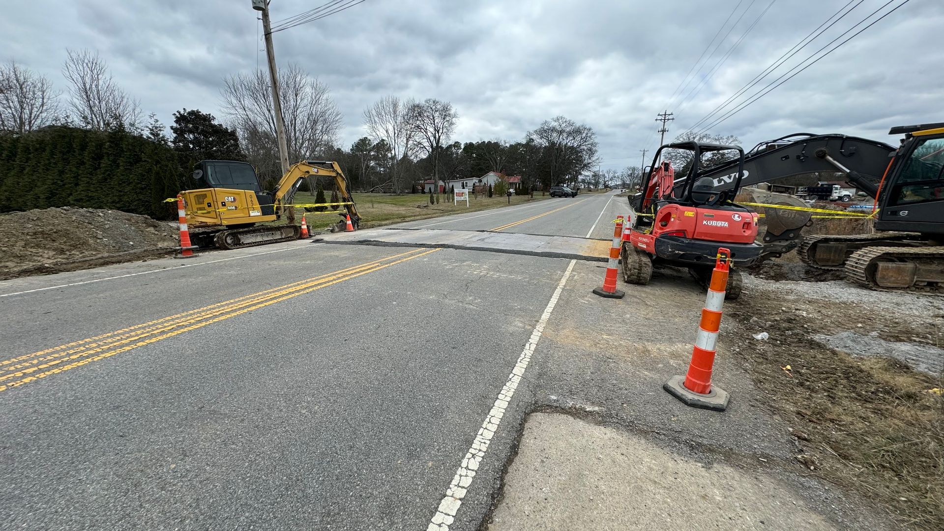 A couple of construction vehicles are sitting on the side of a road.