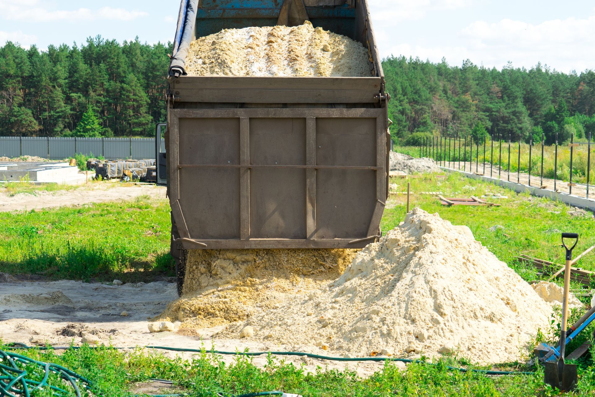 Dump truck unloading a pile of pale sand at a construction site