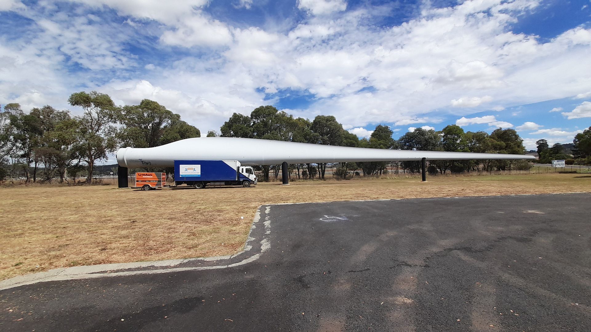 Wide shot of a long white-roofed pavilion beside a paved lot under a partly cloudy sky — TJ Removals and Storage in Wagga Wagga, NSW
