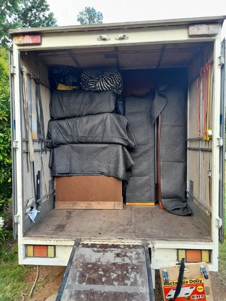 Open truck loaded with stacked furniture and items wrapped in black covers, with a metal ramp down — TJ Removals and Storage in Wagga Wagga, NSW