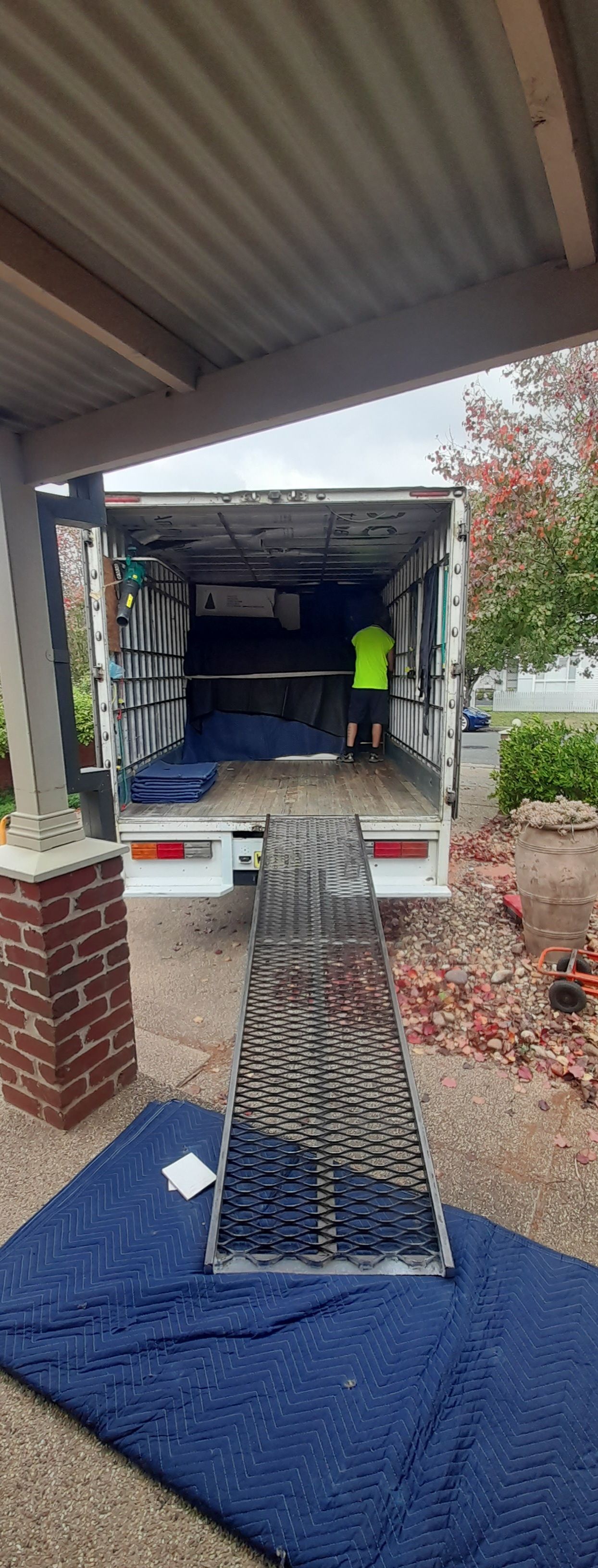 Ramp leads from porch to truck, with a worker in a neon safety vest loading cargo — TJ Removals and Storage in Wagga Wagga, NSW