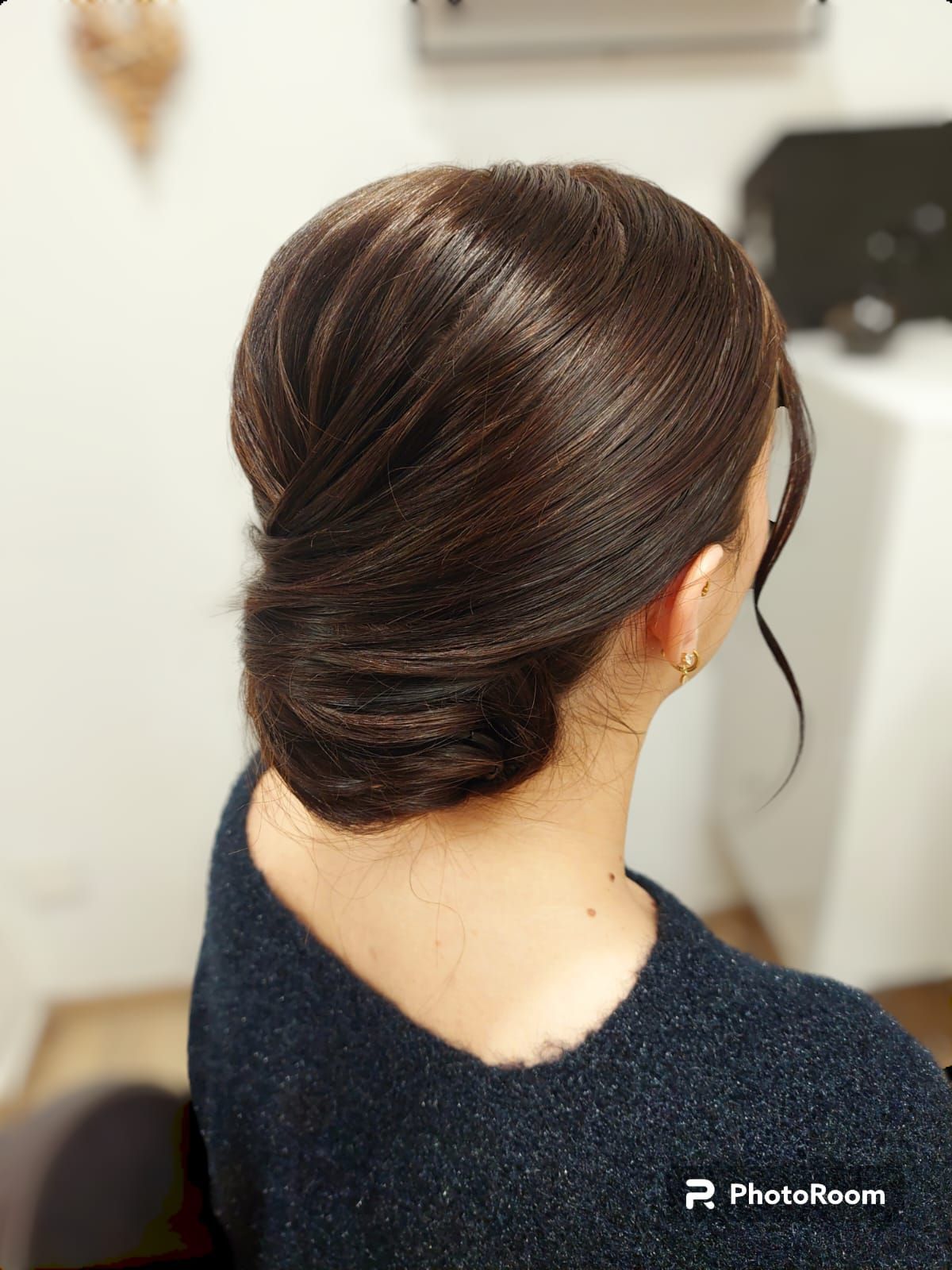 Une femme avec les cheveux en chignon est assise sur une chaise.