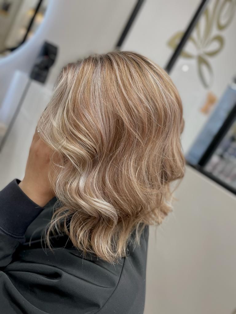 Une femme aux cheveux blonds est assise sur une chaise dans un salon.