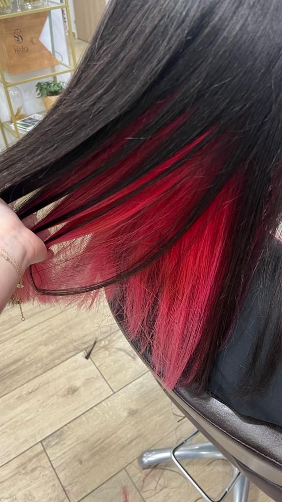 Un gros plan des cheveux d'une personne avec des reflets rouges.