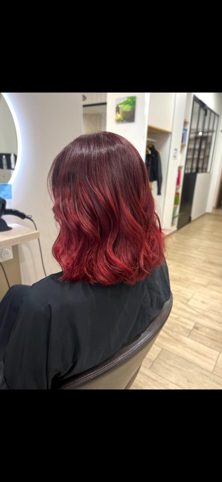 Une femme aux cheveux roux est assise sur une chaise dans un salon.