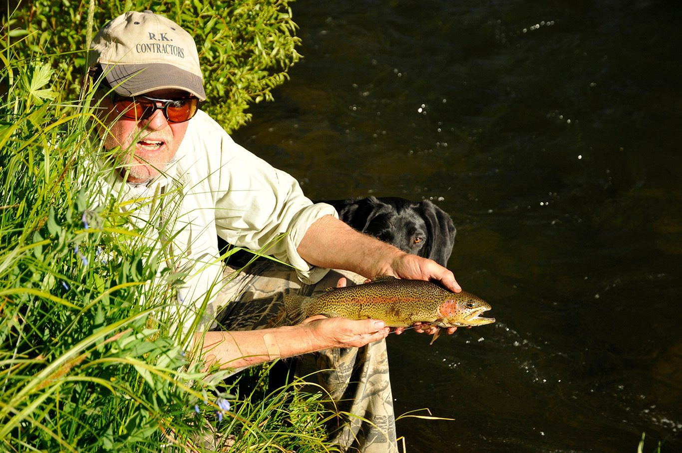 Sterling holds a trout on the bank of a Colorado river.