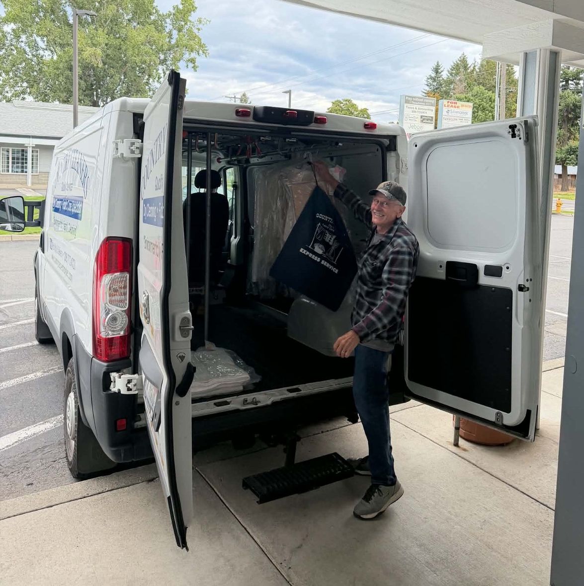 Country Cleaners driver loading cleaned garments into the pickup and delivery van