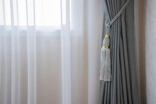 Gray drapes and sheer curtains hanging beside a window