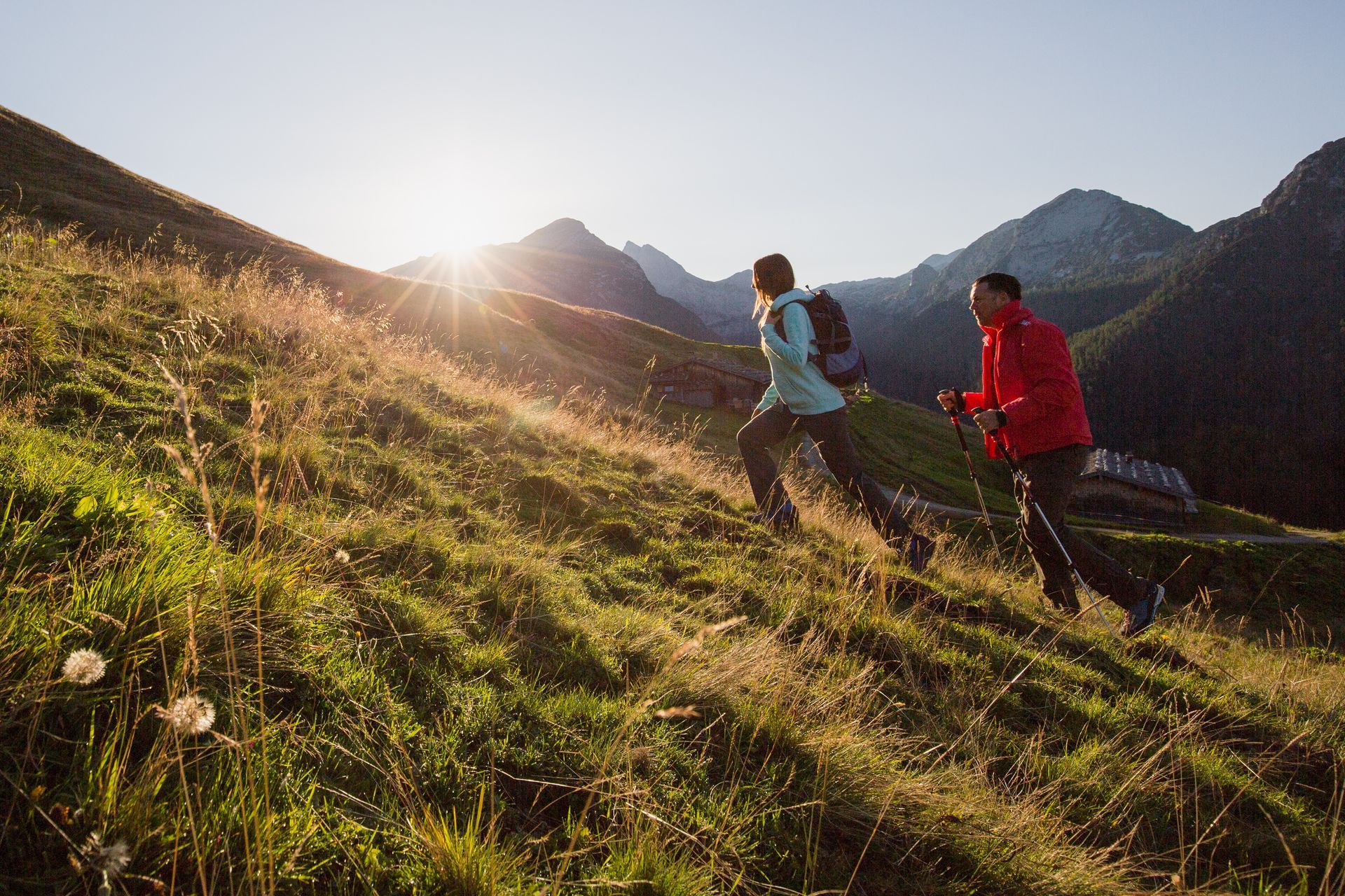 A man and a woman are walking up a grassy hill.