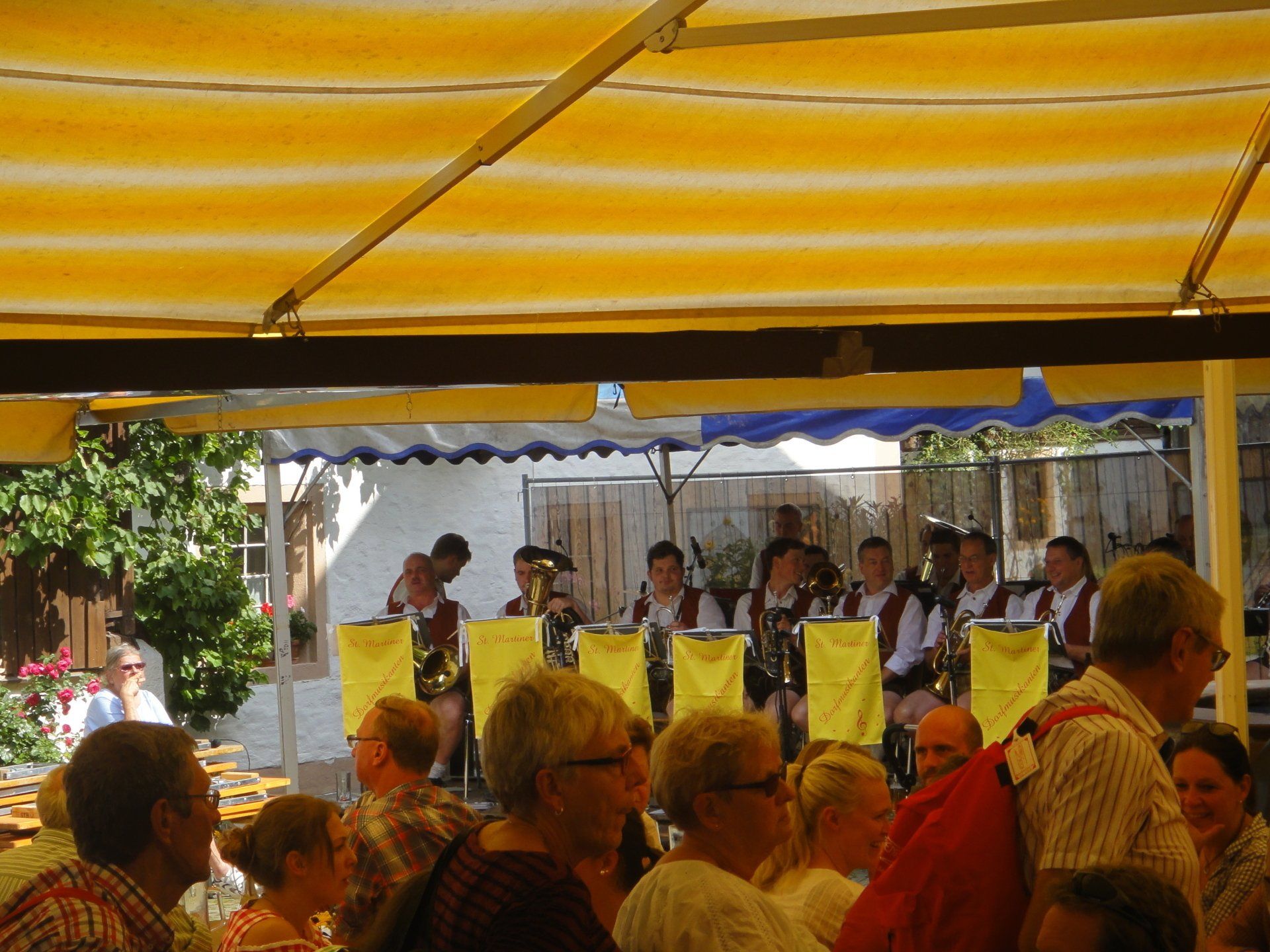 Die Musiker treten auf einer Bühne unter einem gelben Baldachin auf, vor ihnen sitzt ein Publikum.