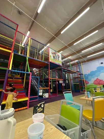 Tree Service Elmonte-Colorful indoor play area with multi-level climbing structures and slides. A child in a yellow dress plays on a rainbow staircase. Bright, lively atmosphere.