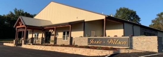 Brick building with a beige metal roof and porch, set behind a stone wall with a sign reading “Lakeside-Hilson.”