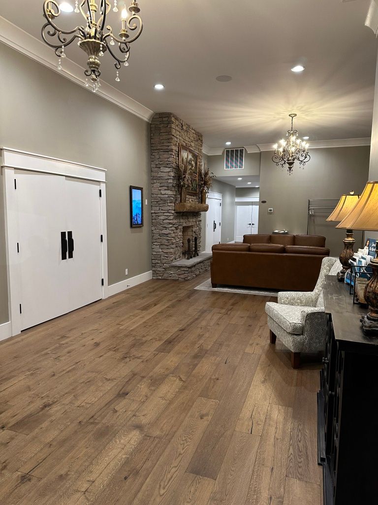 Modern living room with wood floors, stone fireplace, brown sectional sofa, and chandelier lighting