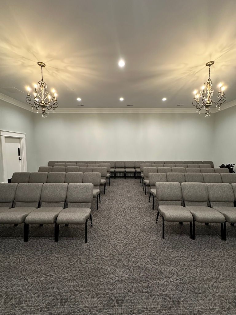 Empty meeting room with gray chairs, chandeliers, and white walls