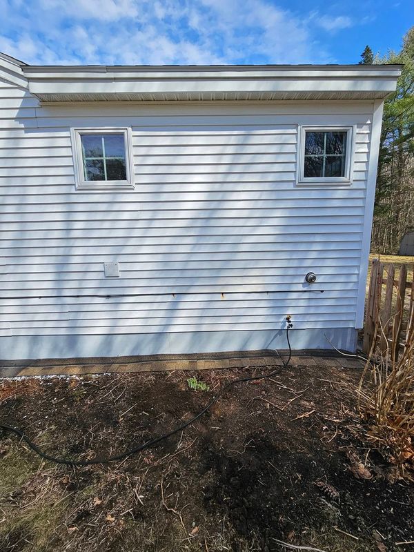 A worker in a lift basket uses a pressure washer to clean a shingled roof on a brick house. A worker in a lift basket uses a pressure washer to clean a shingled roof on a brick house.