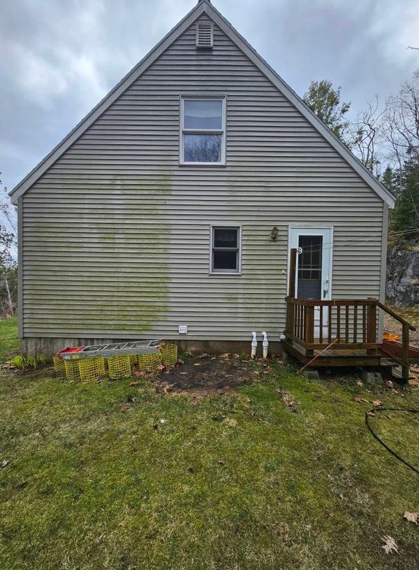 A pressure washer cleans dark, weathered wooden steps, revealing lighter, clean wood underneath over vibrant green grass. A pressure washer cleans dark, weathered wooden steps, revealing lighter, clean wood underneath over vibrant green grass.