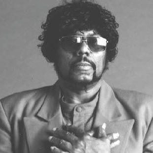 A black and white photo of a man wearing sunglasses and a suit.
