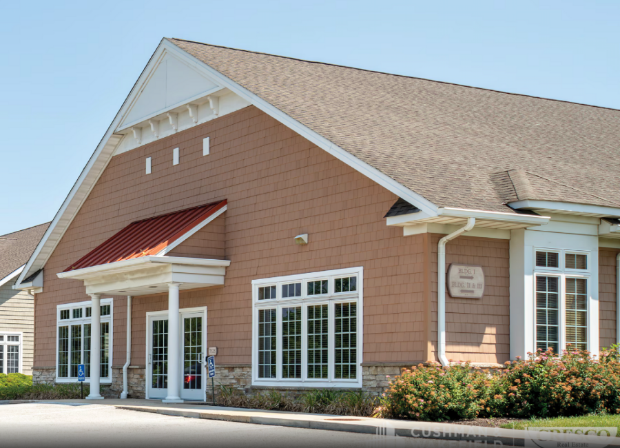 Brick building with a red awning, white trim, and large windows under a tan shingled roof
