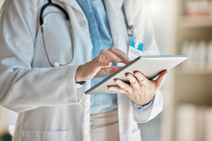 Doctor using a tablet in a bright clinic, with a stethoscope around the neck
