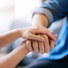 Two hands clasped together in a supportive gesture, with a blurred blue background